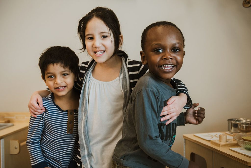 Group of three smiling kids arms around each other